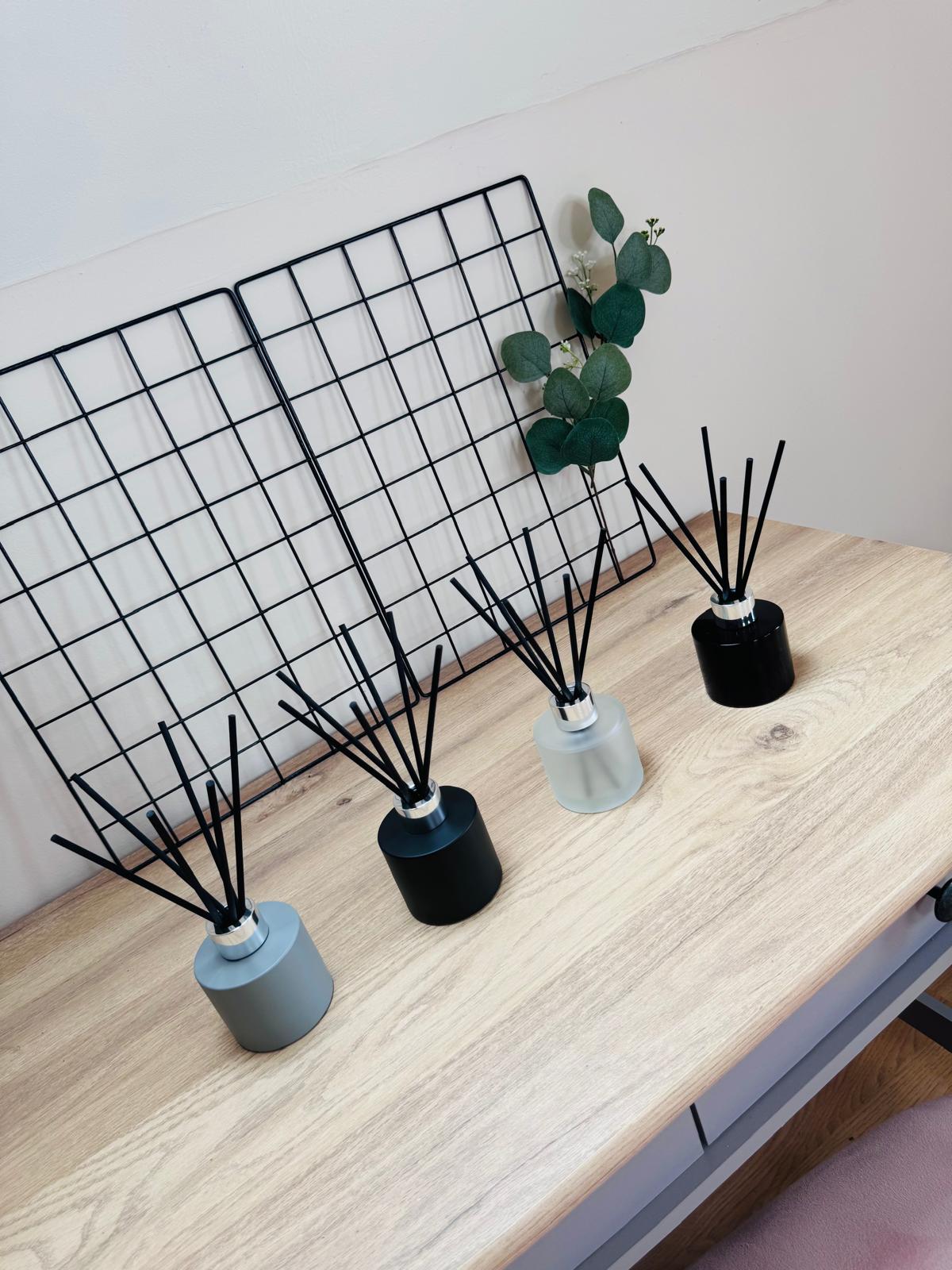 Diffusers on a wooden surface with a grid shelf in the background