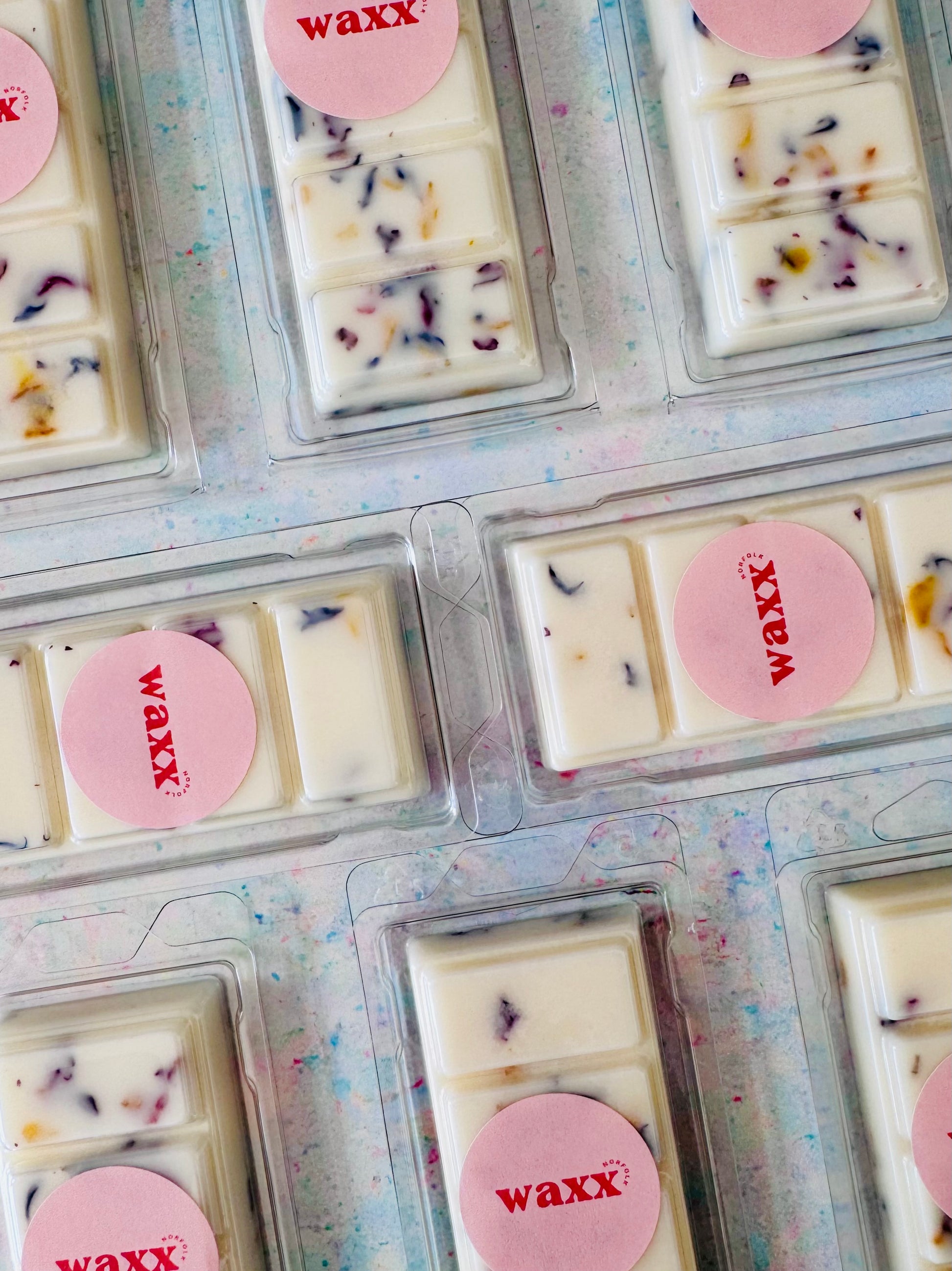 Wax bars in clear packaging with pink 'waxx' labels on a colorful background
