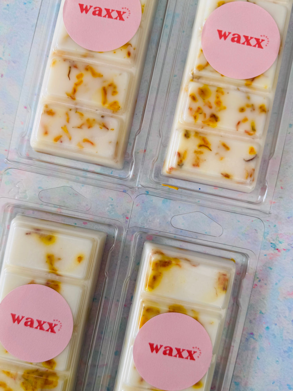 Four wax melts in packaging with 'waxx' label on a light background